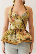 Woman wearing a chinoiserie patterned halter peplum top with a white background