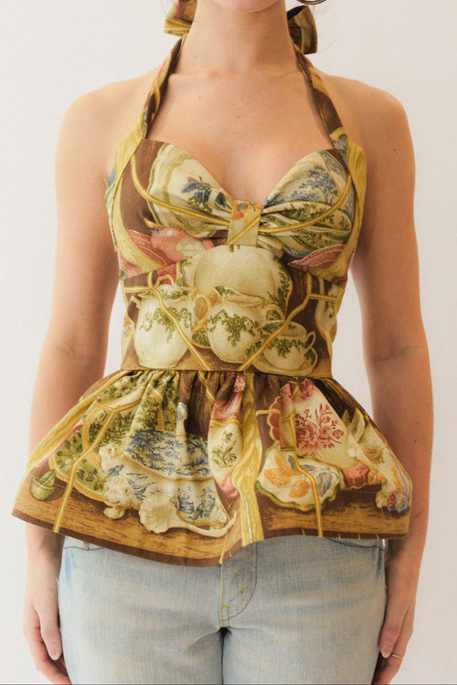 Woman wearing a chinoiserie patterned halter peplum top with a white background