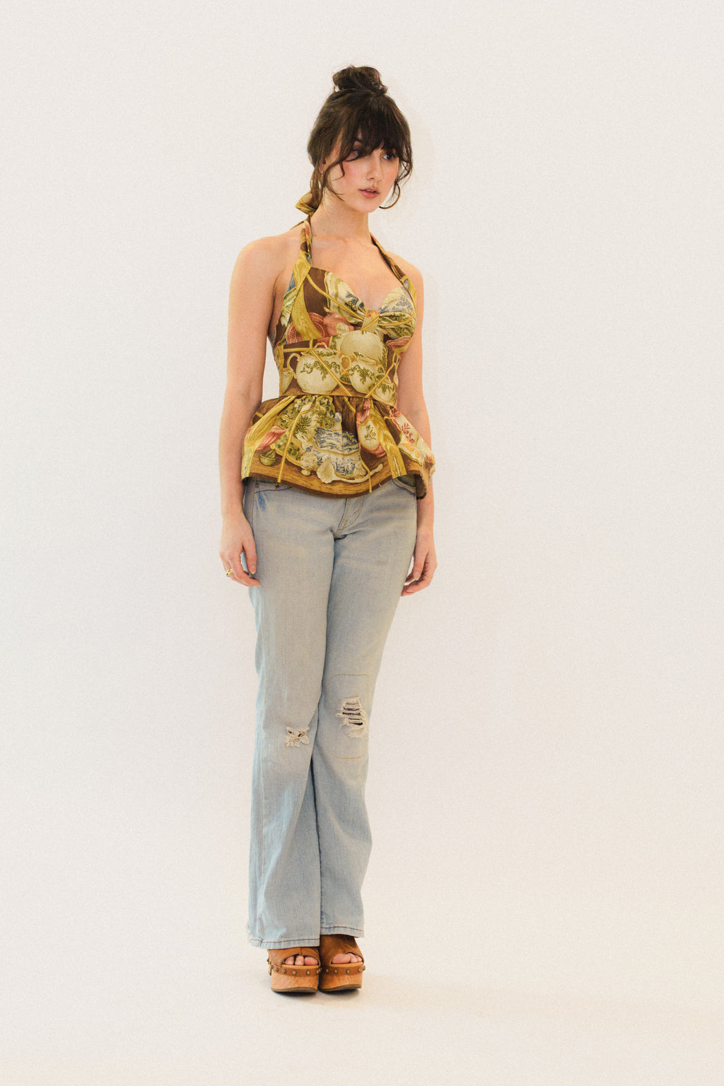 Woman wearing a chinoiserie pattern top and light blue jeans on a white background