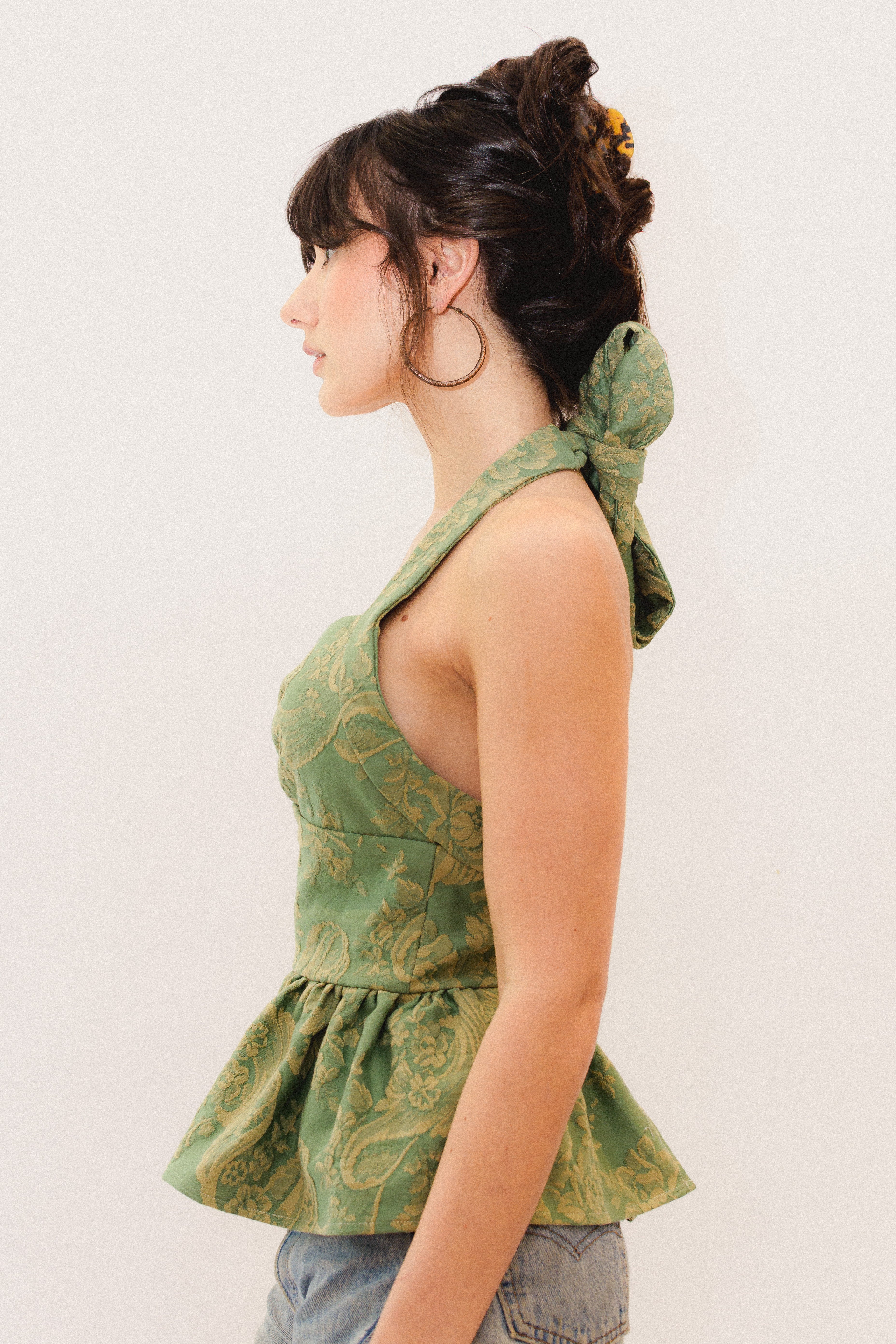 Woman wearing a green patterned top with a plain background