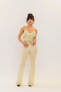 Woman wearing a cream fringe top and pants on a white background
