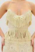 Woman wearing a cream lace fringe corset top against a white background