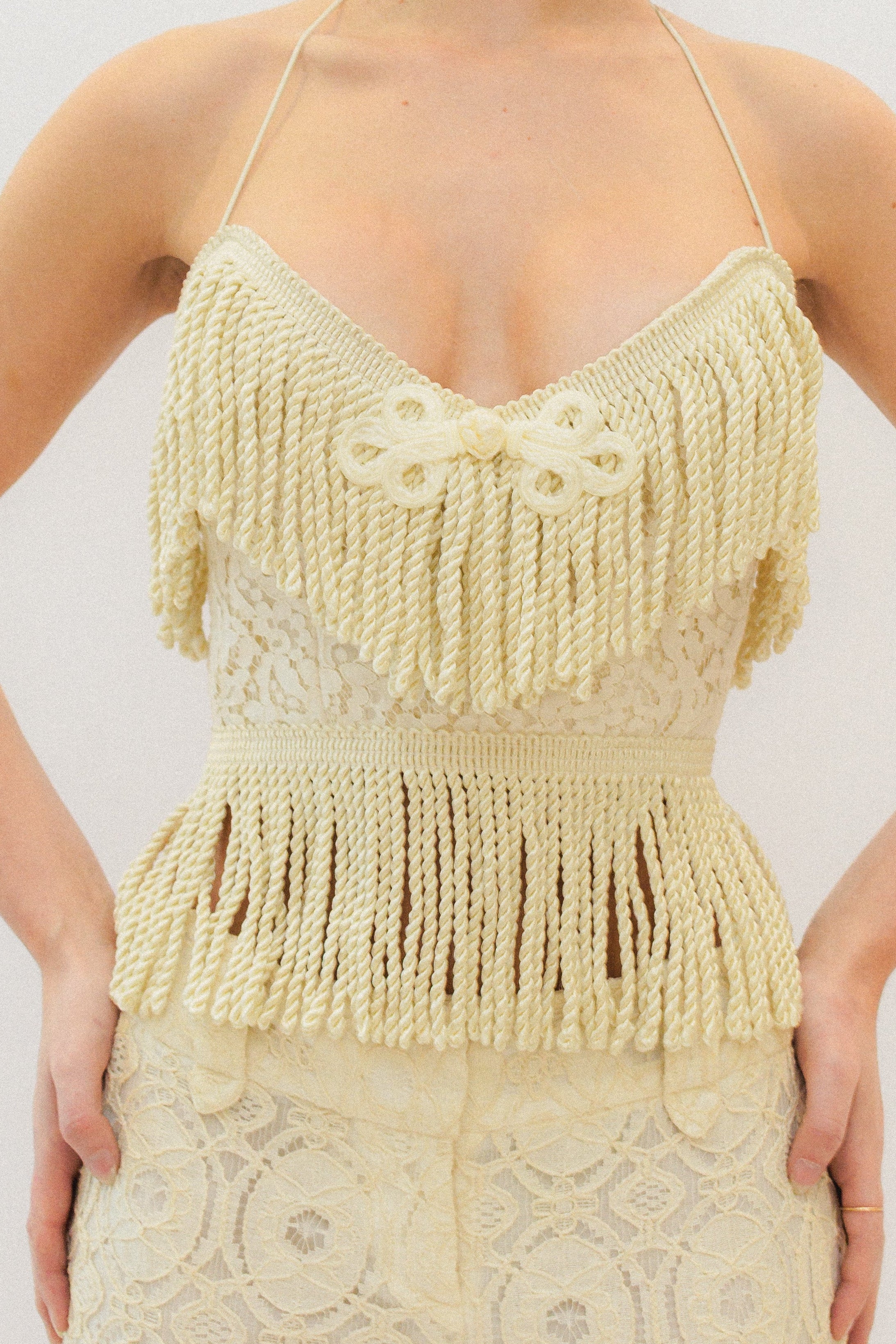 Woman wearing a cream lace fringe corset top against a white background