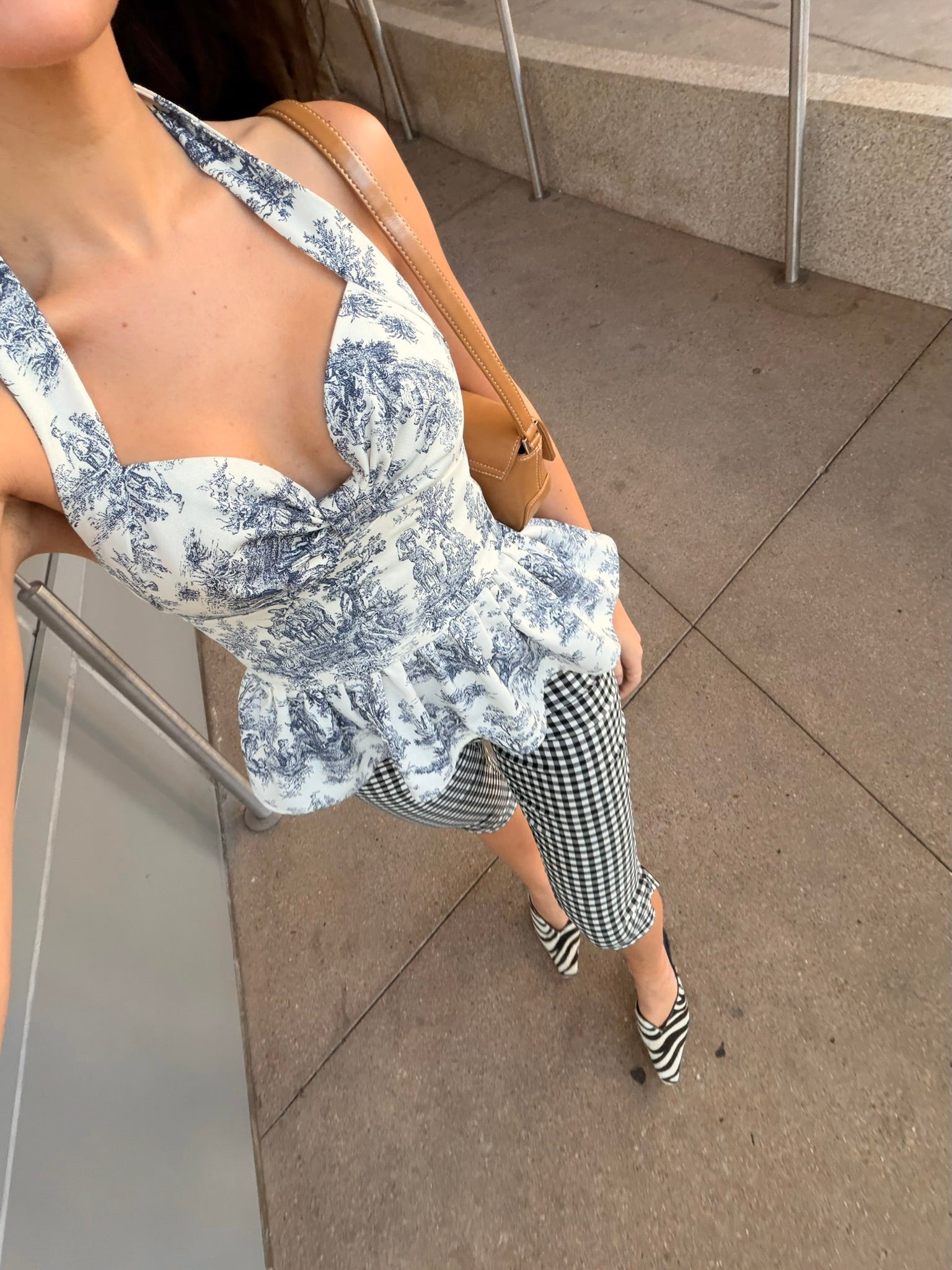 Woman wearing a black and white toile halter top and checkered capris on a sidewalk.