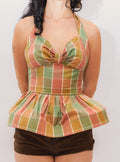 Woman wearing a colorful plaid peplum top against a plain background