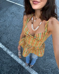 Woman wearing a colorful gingham plaid peplum halter top standing on a street.