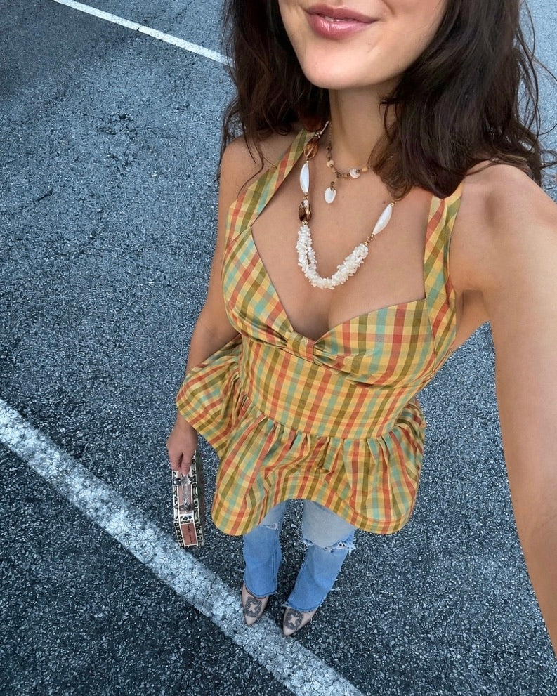 Woman wearing a colorful gingham plaid peplum halter top standing on a street.