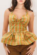 Woman wearing a colorful plaid top with a peplum waist against a plain background