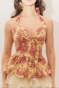 Woman wearing a yellow and red patterned halter top with ruffled details.