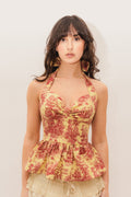 Woman wearing a yellow and red toile de jouy halter peplum top against a plain background