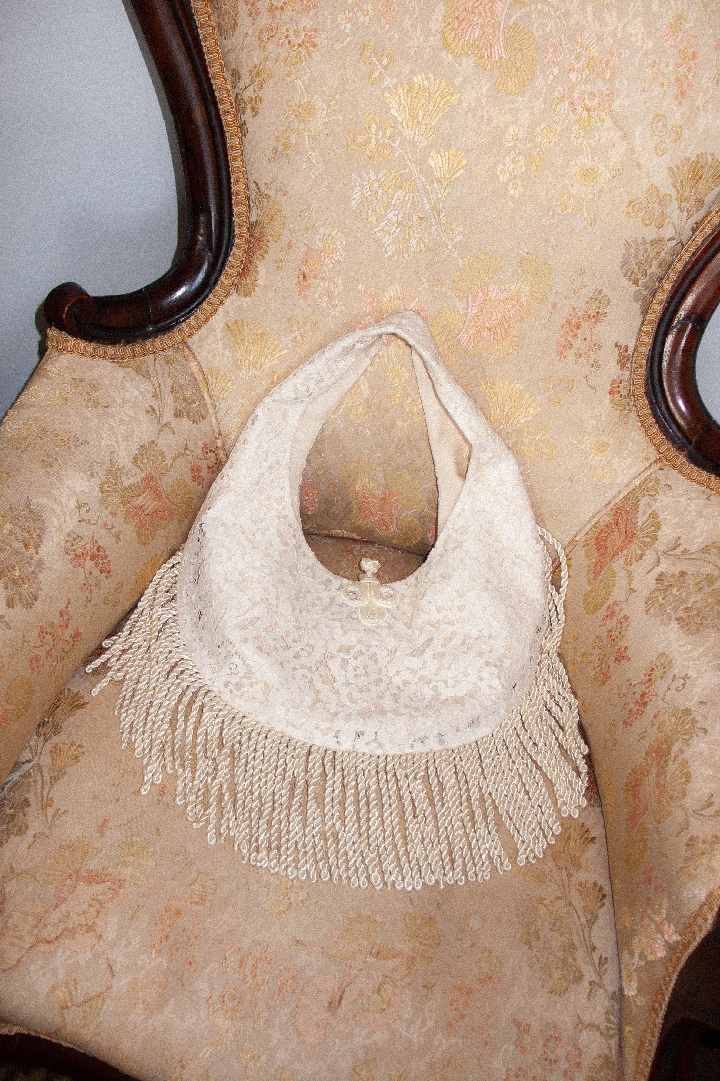 White handbag with fringe details on a vintage chair