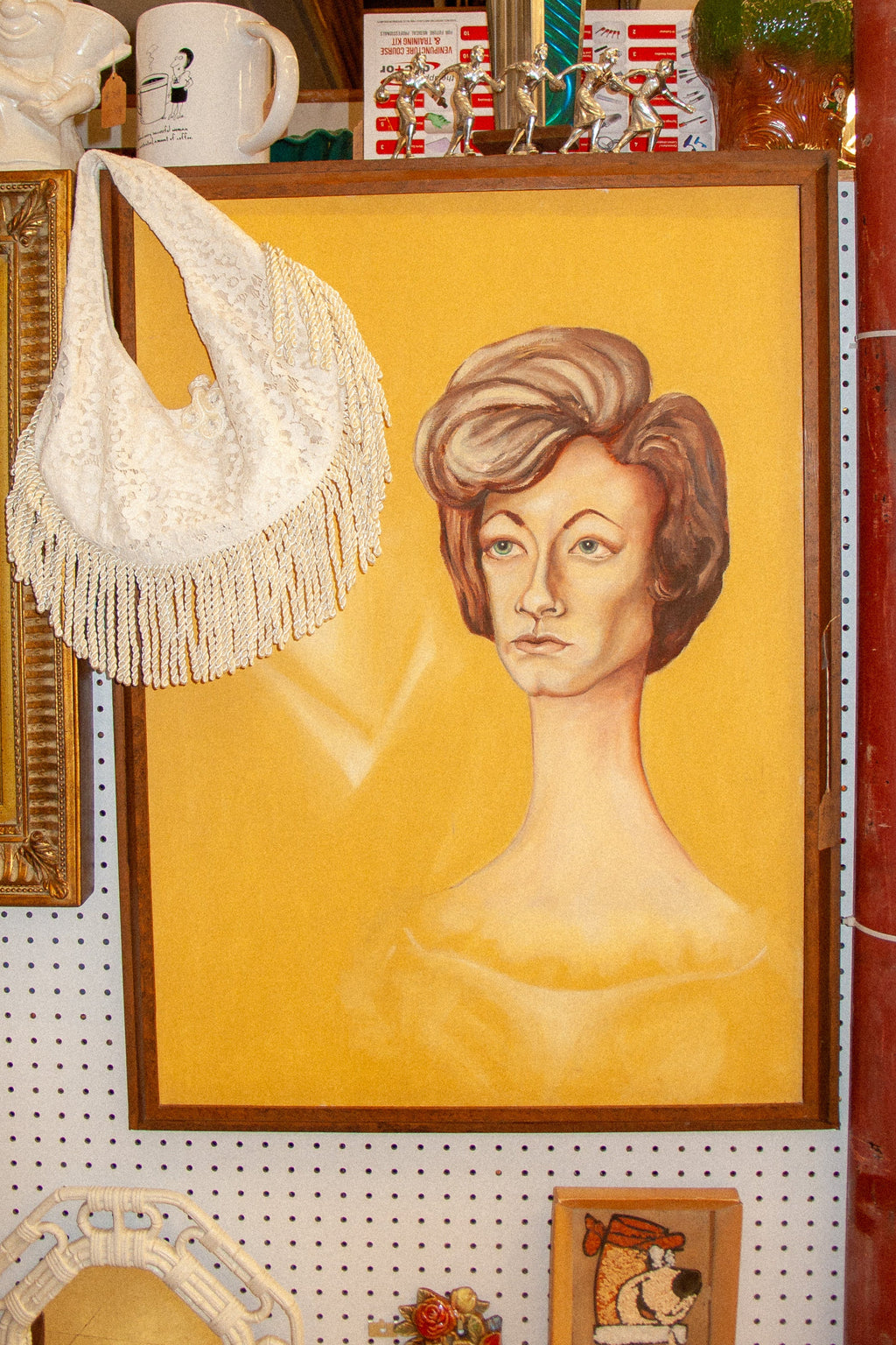 Vintage-style interior with a framed portrait of a woman looking at cream lace fringe bag
