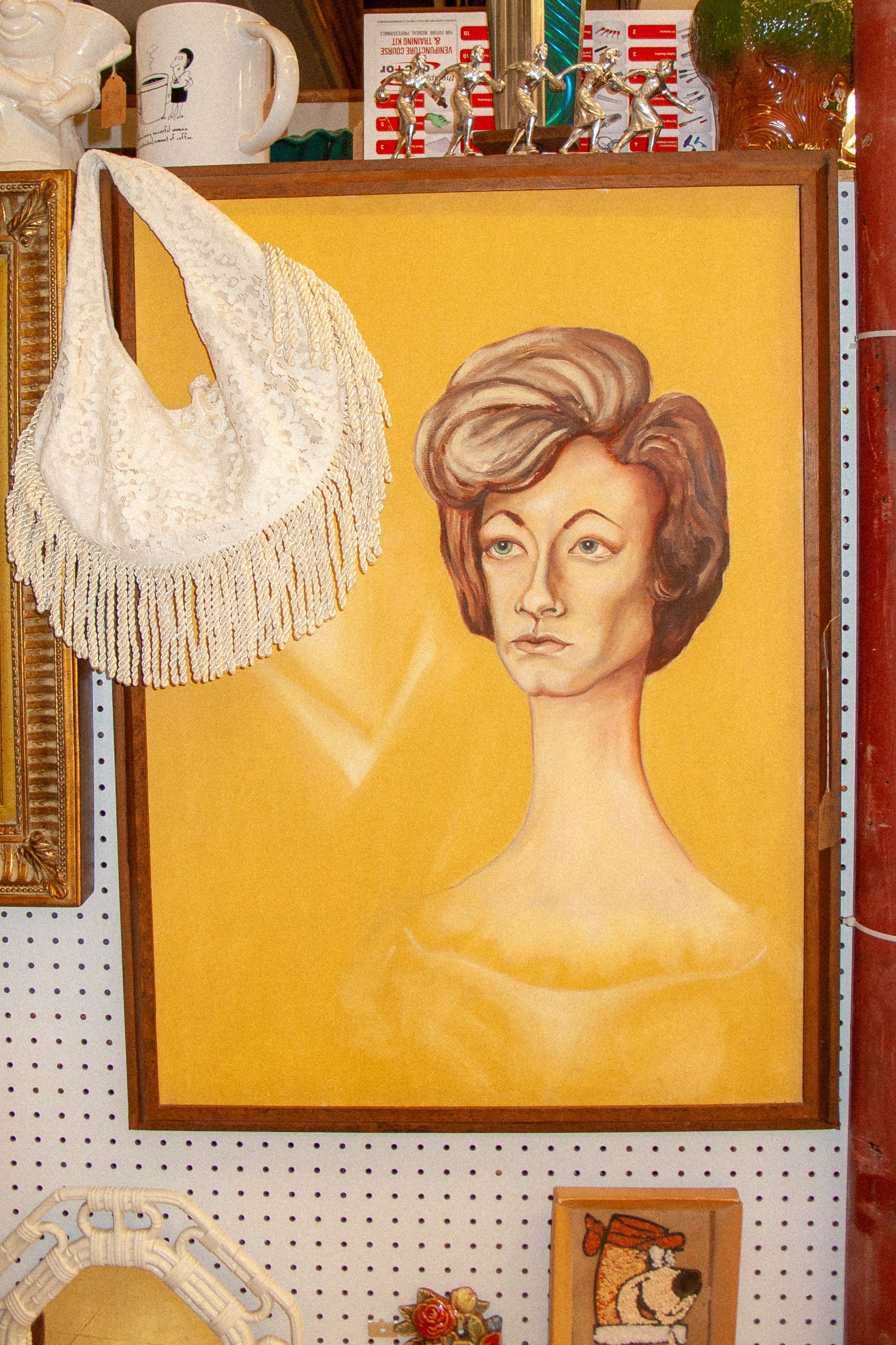 Vintage-style interior with a framed portrait of a woman looking at cream lace fringe bag