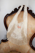 Cream lace mesh bag with fringe details on a vintage chair